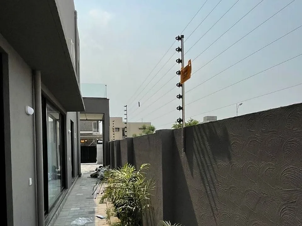 Wall-top electric fence with warning sign installed by CSO on a residential wall
